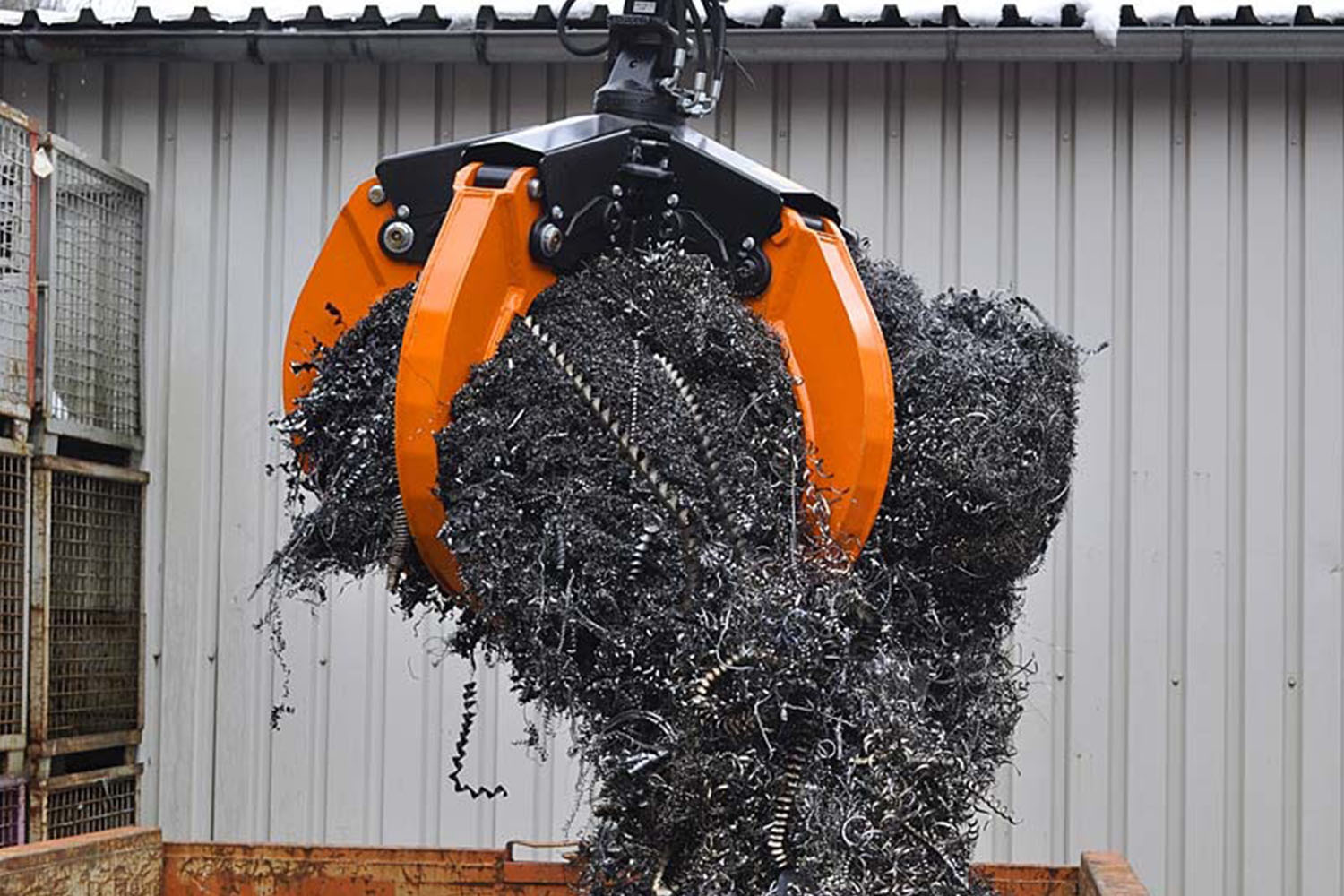 scrap metal wires being picked up by an orange peel grab